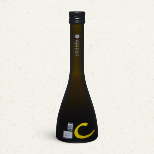Tall dark glass bottle of Alexis Muñoz lemon olive oil with a flared base and a yellow letter C