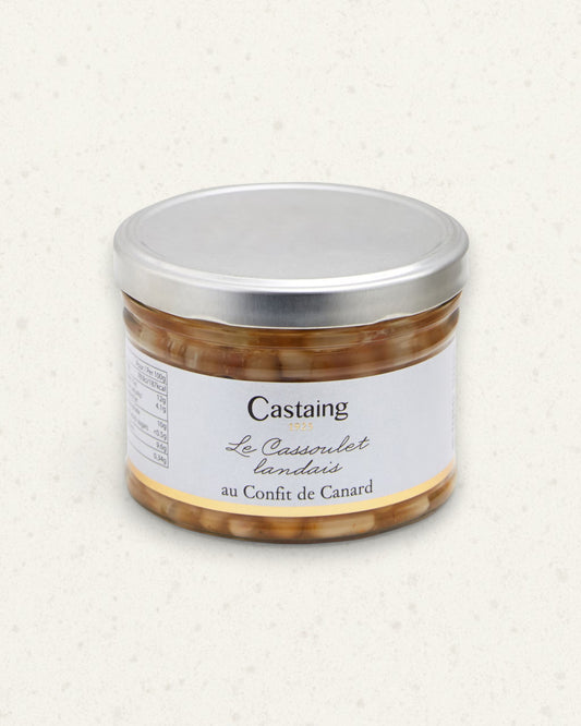 Wide glass jar of Castaing cassoulet with duck confit, silver lid and white label, beans visible inside