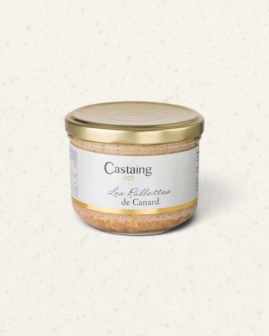 Wide glass jar of Castaing duck rillettes with a gold lid and a white label, on a light background