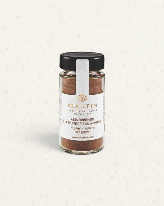 Tall glass jar of Plantin summer truffle seasoning with a black lid and white label, brown seasoning inside
